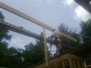 Carpenter setting a ridge beam over a new addition frame — Ice Dam Removal by Roofing Brothers in Bellaire
