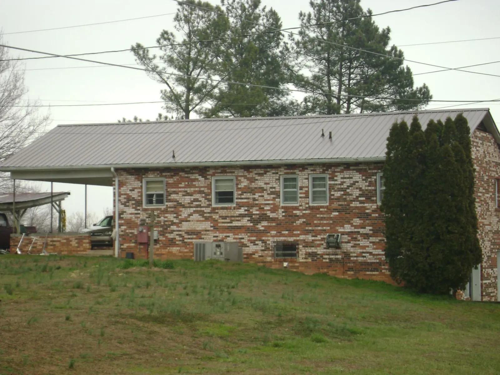 Gray metal roof on a brick split level home with a carport in Bellaire