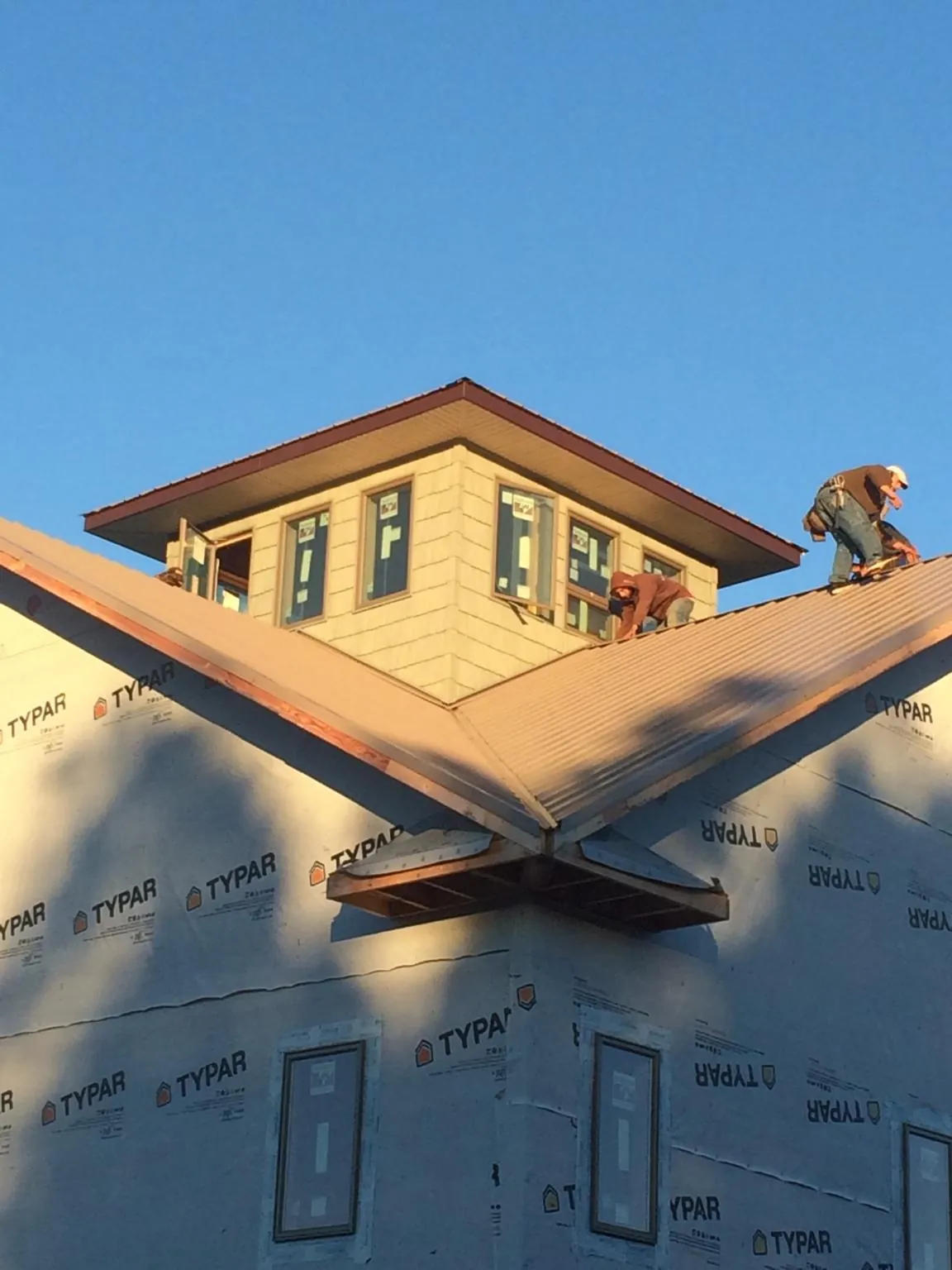 Roofers working around a rooftop cupola on a new metal roof at sunset — Roof Waterproofing in Bellaire by Roofing Brothers